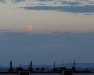 red moon shining above skyline on a cloudy evening