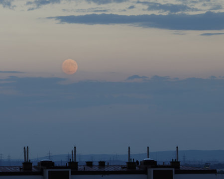 red moon shining above skyline on a cloudy evening