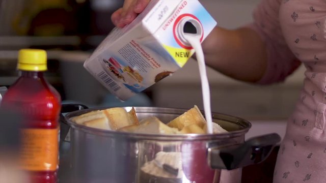 Woman spilling milk onto a pot of bread before cooking Abar&aacute;