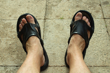 Men's legs in beach slippers. Close-up. Background.