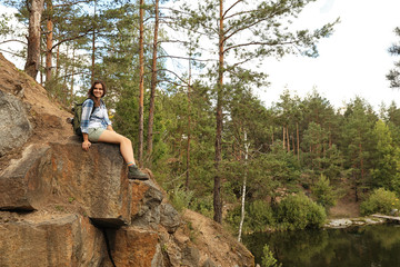 Young woman on rocky mountain near forest. Camping season