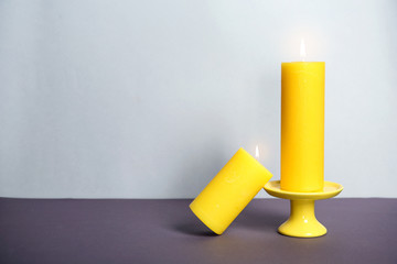 Decorative wax candles on table against light background