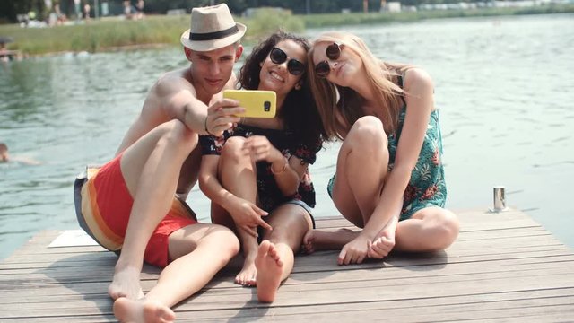 Group of friends making selfies by the lake.