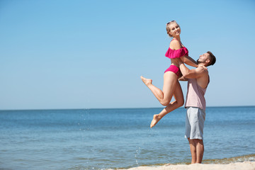 Happy young couple having fun at beach on sunny day