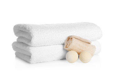 Stack of clean soft towels, bath bombs and sponge on white background