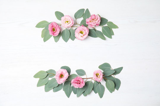 Fresh eucalyptus leaves with flowers and space for design on white wooden background, flat lay