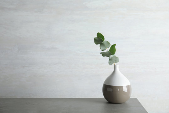 Vase with eucalyptus branch with fresh leaves on table