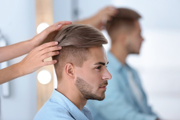 Professional hairdresser working with young man in barbershop. Trendy hair color - Powered by Adobe