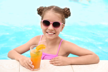 Little girl with cocktail in pool on sunny day