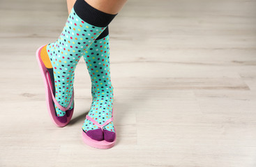 Woman wearing bright socks with flip-flops standing on floor. Space for design