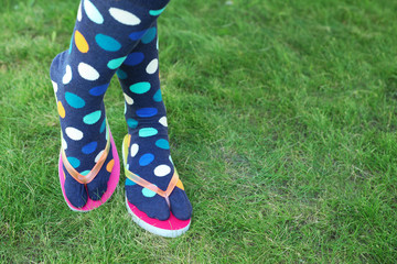 Woman wearing bright socks with flip-flops standing on grass. Space for design