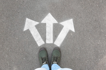 Woman standing near arrows on asphalt, top view. Choice concept