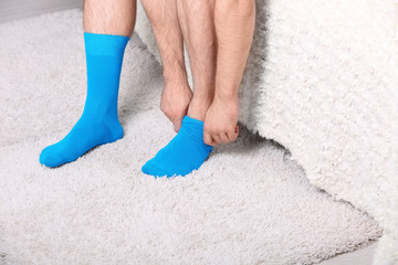 Man putting on stylish socks in bedroom, closeup