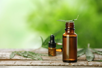 Bottle with hemp extract on table and space for text against blurred background