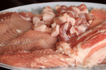 Raw pork cut into pieces in the dish. Include bacon, meat and streaky pork in the plate.