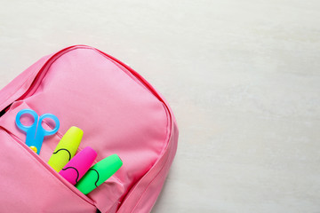 Backpack with school stationery on light background, top view and space for text