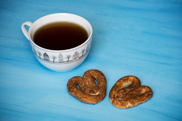Poppy with pretzels on a blue board with a cup of tea. A cup of tea and pretzels with cinnamon.