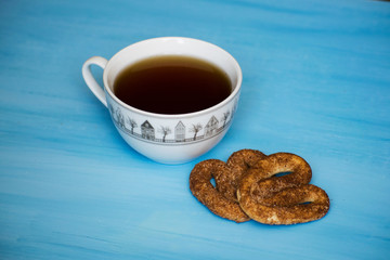 Poppy with pretzels on a blue board with a cup of tea. A cup of tea and pretzels with cinnamon.