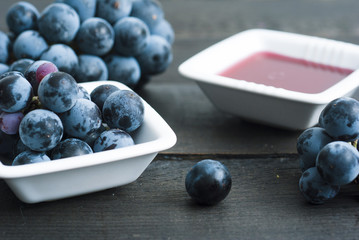 red grape juice in china bowl, black wood table background