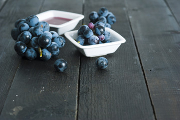 red grape juice in china bowl, black wood table background