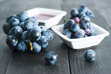 red grape juice in china bowl, black wood table background