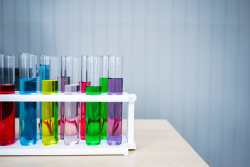 Rack with test tubes, laboratory glassware, with colorful chemical liquids on table with clean white background. Chemical analysis. Science concept.