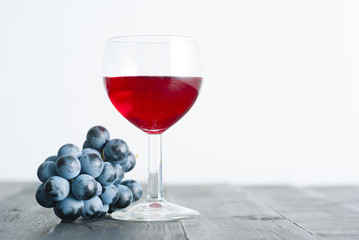 glass of red wine and grapes on black wood table background