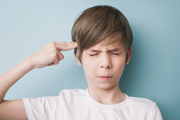 Boy depicts shot from pistol, holding forefinger at his temple