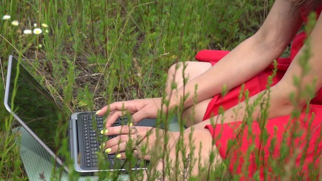 Young trendy woman typing keyboard. Girl using laptop outside.