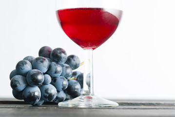 glass of red wine and grapes on black wood table background