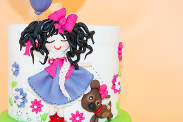A Cake With a Dolly with Long Black Hair and Baloons made with Sugar Paste on Orange Background