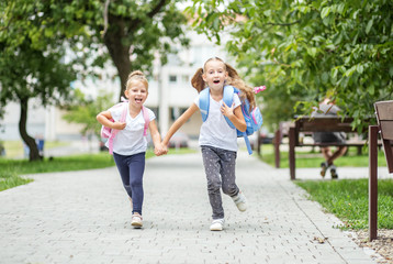 Happy children run from school with backpacks. The concept of school, study, education, friendship, childhood.