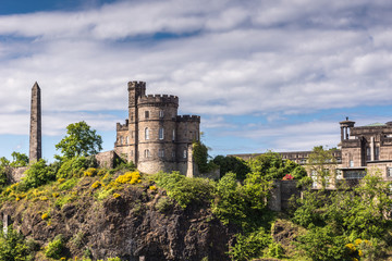 Edinburgh, Scotland, UK - June 13, 2012: Martyrs of reform Monument and Governor House of Old Calton Jail on green cliff under cloudy sky.