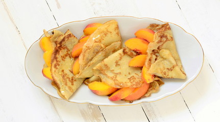 Delicious pancakes with peaches and honey for breakfast