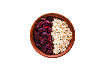 Raw oatmeal with dried cranberries in a round clay bowl on a dark wooden background. Healthy fitness vegetarian breakfast granola meal with cranberries. Top view