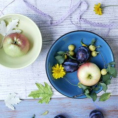 Decorative seasonal composition, on a light wooden background fruits, vegetables, autumn leaves and flowers, top view