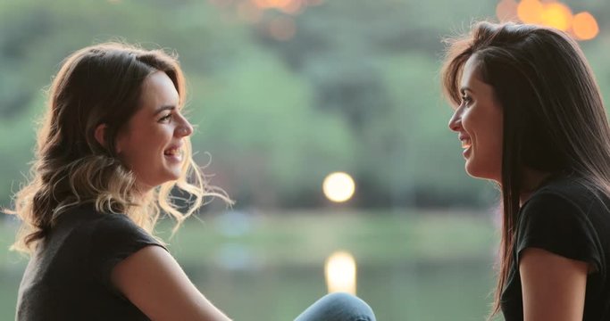 Friends gossiping and exchanging ideas in conversation outdoors in the sunlight by park lake2