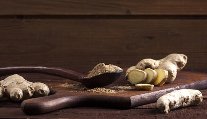 Ginger root and ginger powder on wooden background