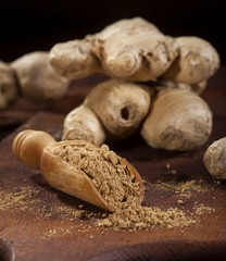 Ginger root and ginger powder on wooden background