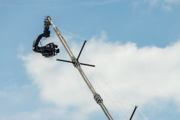 Fototapeta premium Outdoors tv digital video camera on crane on football match isolated blue cloudy sky background