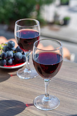Two wine glasses with red wine served with red grape on outdoor terrace
