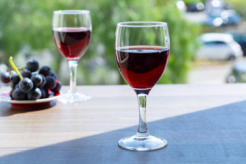 Two wine glasses with red wine served with red grape on outdoor terrace