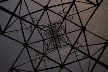 Bottom low angled view of beautiful dark blue starry sky from inside of high voltage tower.