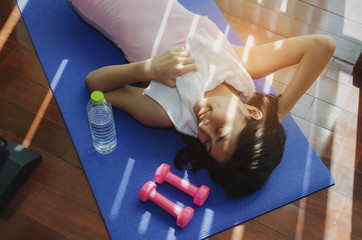 asian young pretty woman slim body with white towel relaxing and lying on floor with yoga mat,...