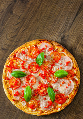 Pizza with Mozzarella cheese, Ham, Tomatoes, pepper, Spices and Fresh Basil. Italian pizza on wooden background. with copy space. top view