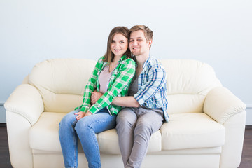 Portrait of a young loving couple resting on a couch together at home and hugging.