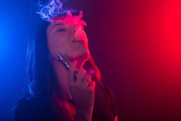 Young woman in black t-shirt vaping in red and blue neon light