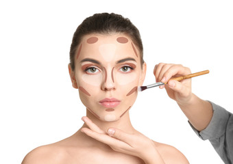 Visage artist applying makeup on woman's face against white background. Professional cosmetic products