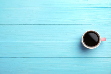 Ceramic cup with hot aromatic coffee on wooden background, top view