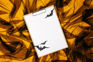 Black and orange abstract background with clipboard and bats, concept for Halloween.